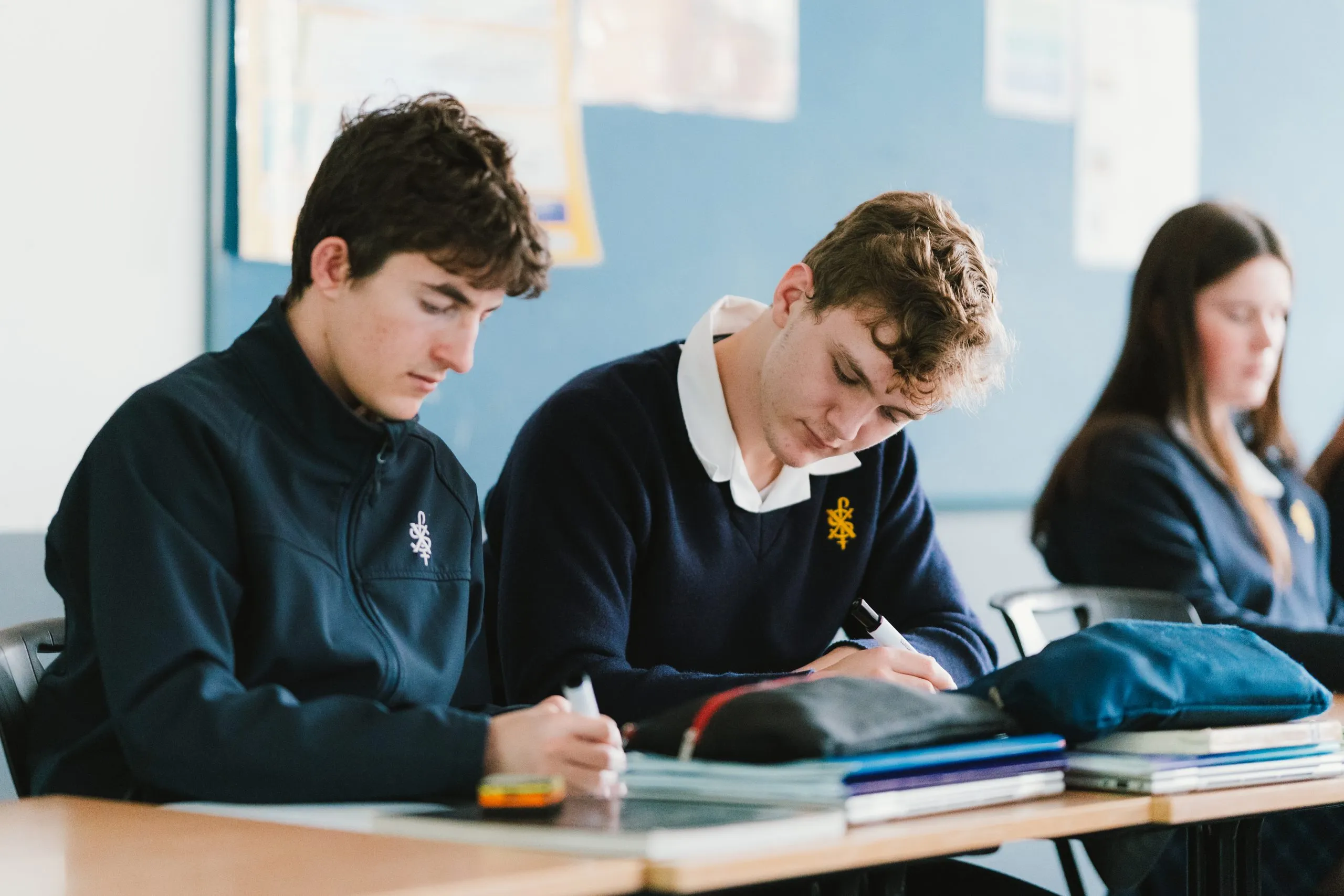 Three students at their desks writing