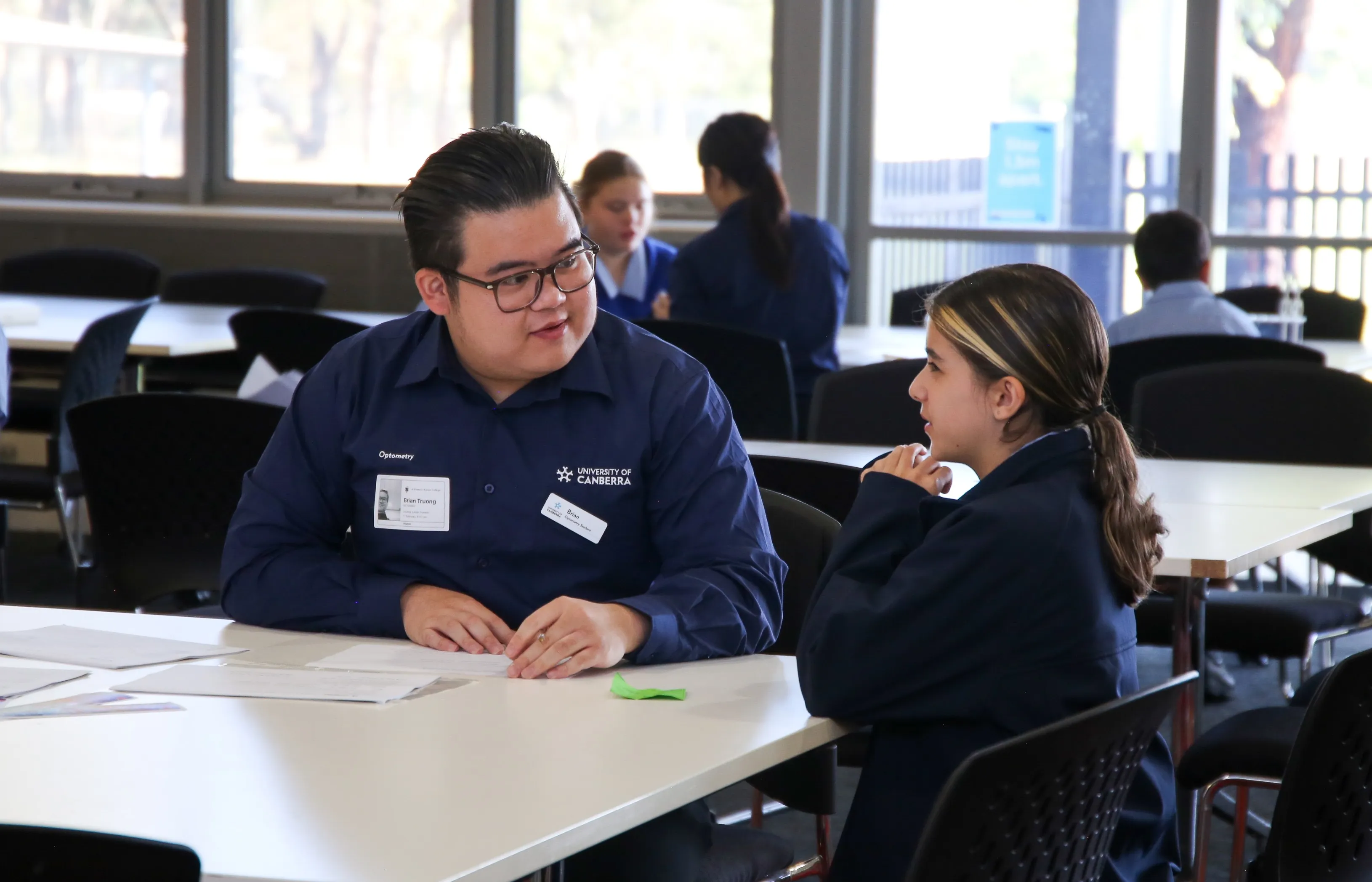 A male university student talking to a younger female high school student