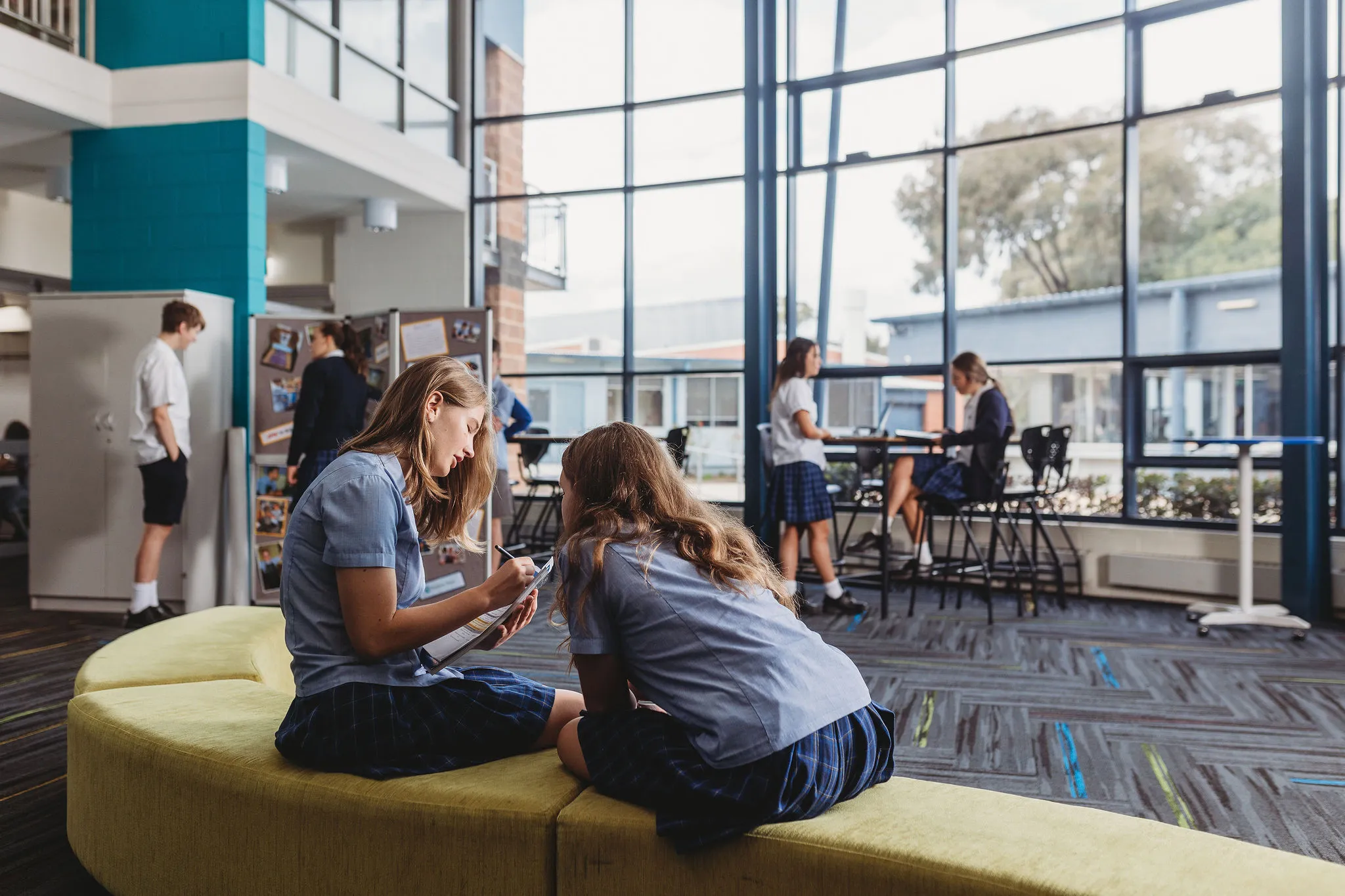 Two students sitting on a couch talking and writing